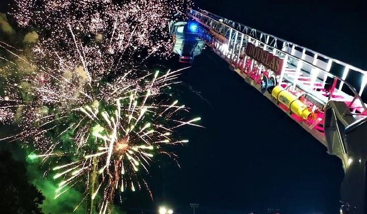 Image of Fire truck ladder and fireworks in the background