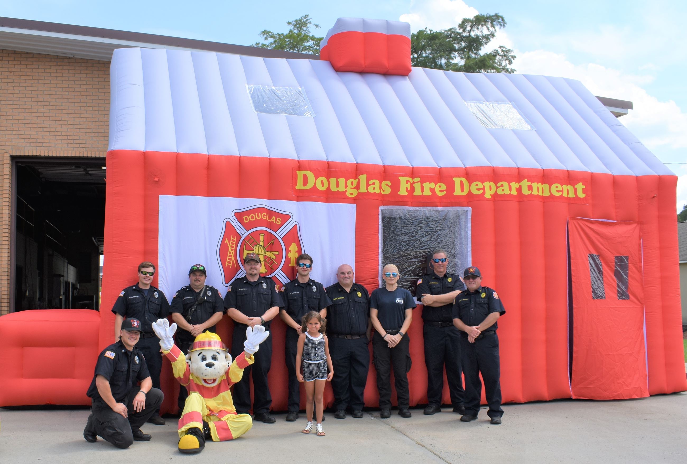 Photo of Firefighters with Child in front of Inflatable Safety House