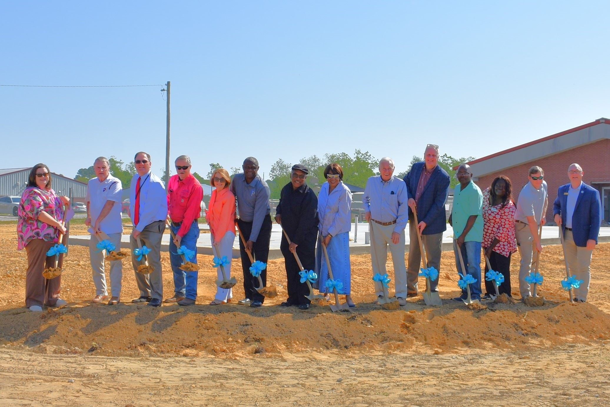 Group of women and men in a line with shovels in dirt 