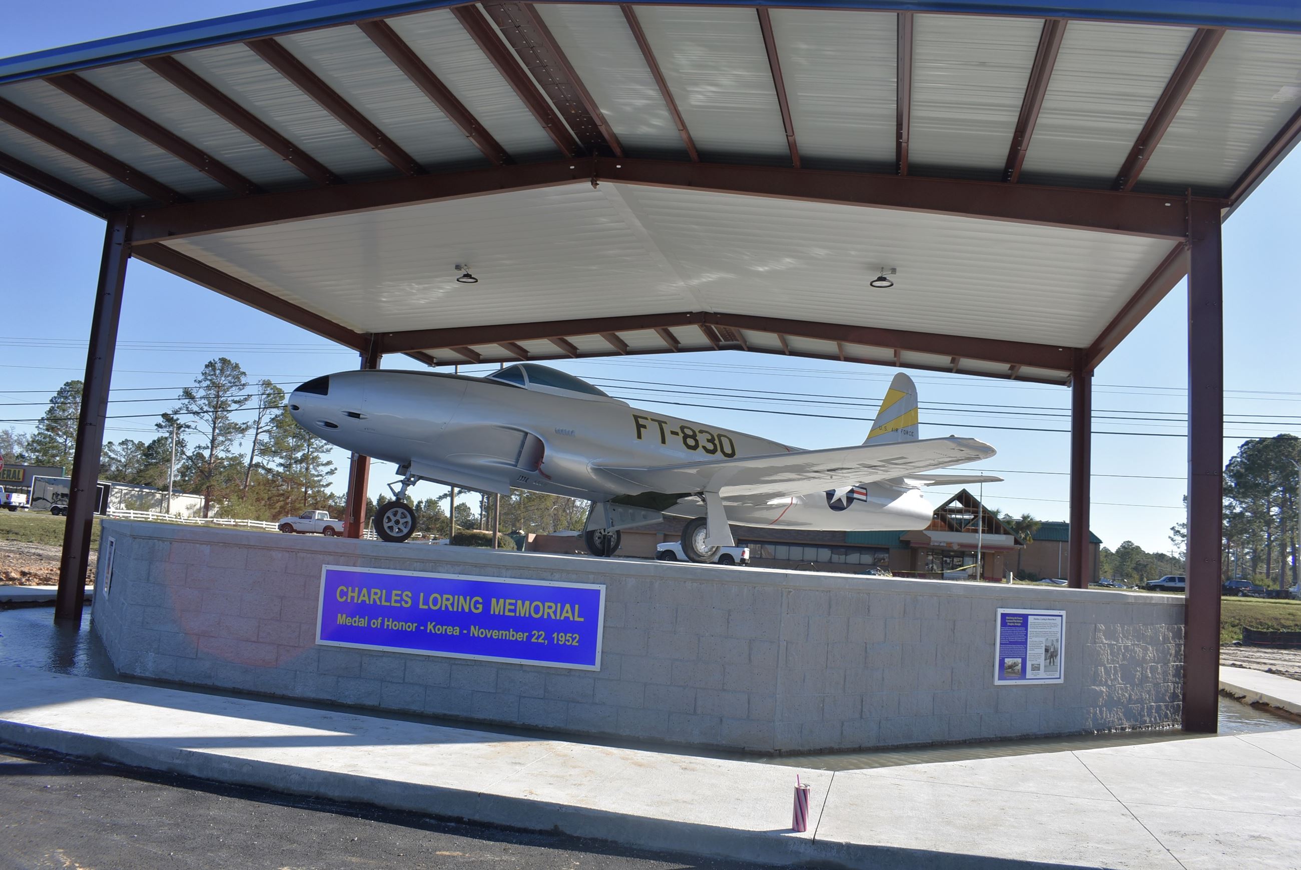 Image of silver airplane with yellow stripe on the tail end and the letters FT-830 in the middle on a pedestal with a shelter over it